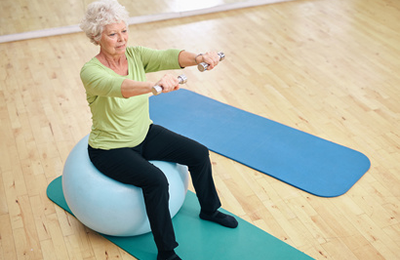 Gleichgewichtsübung einer Patienten, die auf einem Gymnastikball sitzt